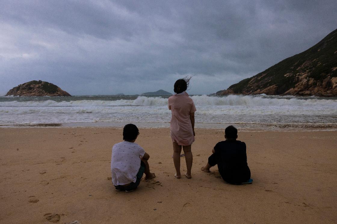 Members of the public look at the waves at a beach during a typhoon in Hong Kong, Monday, July 17, 2023. Schools and the stock market were closed in Hong Kong on Monday as Typhoon Talim swept south of the city. (AP Photo/Louise Delmotte)
