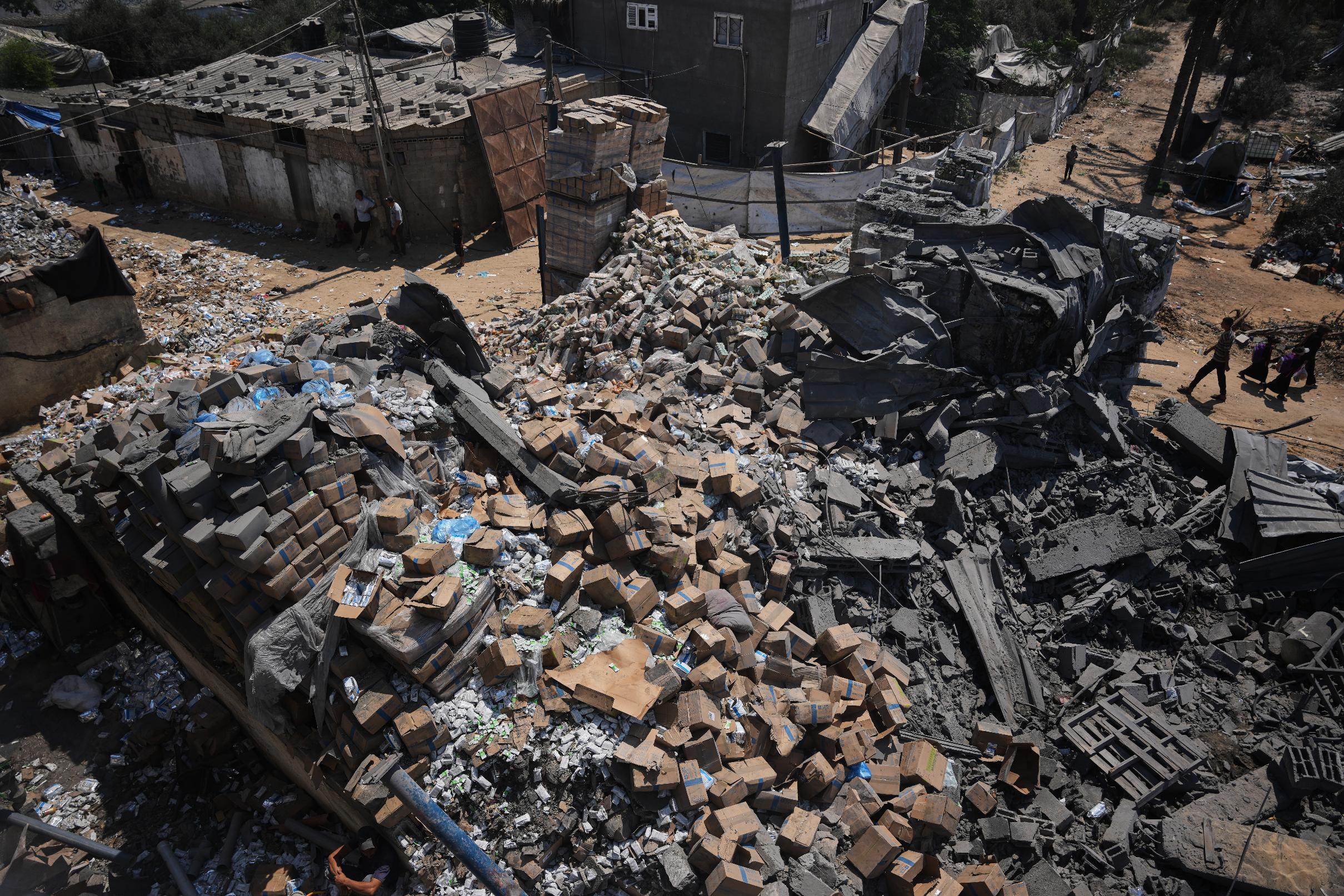 Palestinians walk past a food-aid warehouse damaged in an Israeli airstrike that targeted a nearby house in Deir al-Balah, central Gaza Strip, Wednesday, Aug. 26, 2026. (AP Photo/Abdel Kareem Hana)
