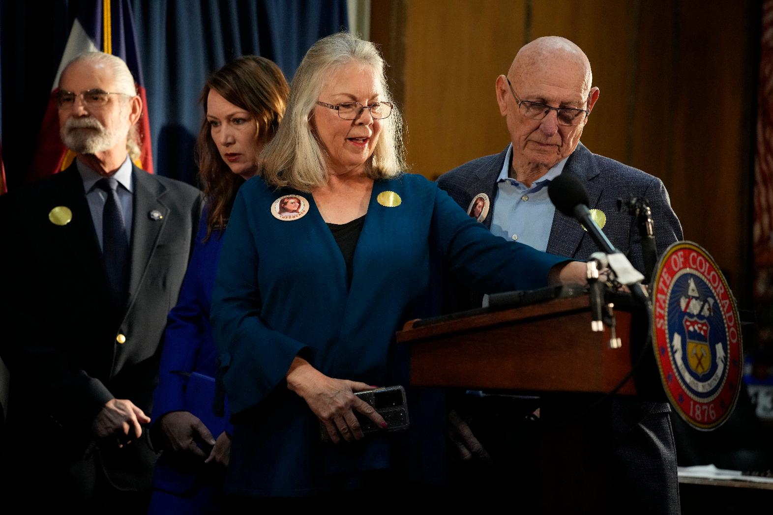FILE — Sandy and Lonnie Phillips, who lost their daughter in the mass shooting at a theatre in Aurora, Colo., look on before Colorado Governor Jared Polis signs four gun control bills into law during a ceremony Friday, April 28, 2023, in the State Capitol in Denver. (AP Photo/David Zalubowski, File)