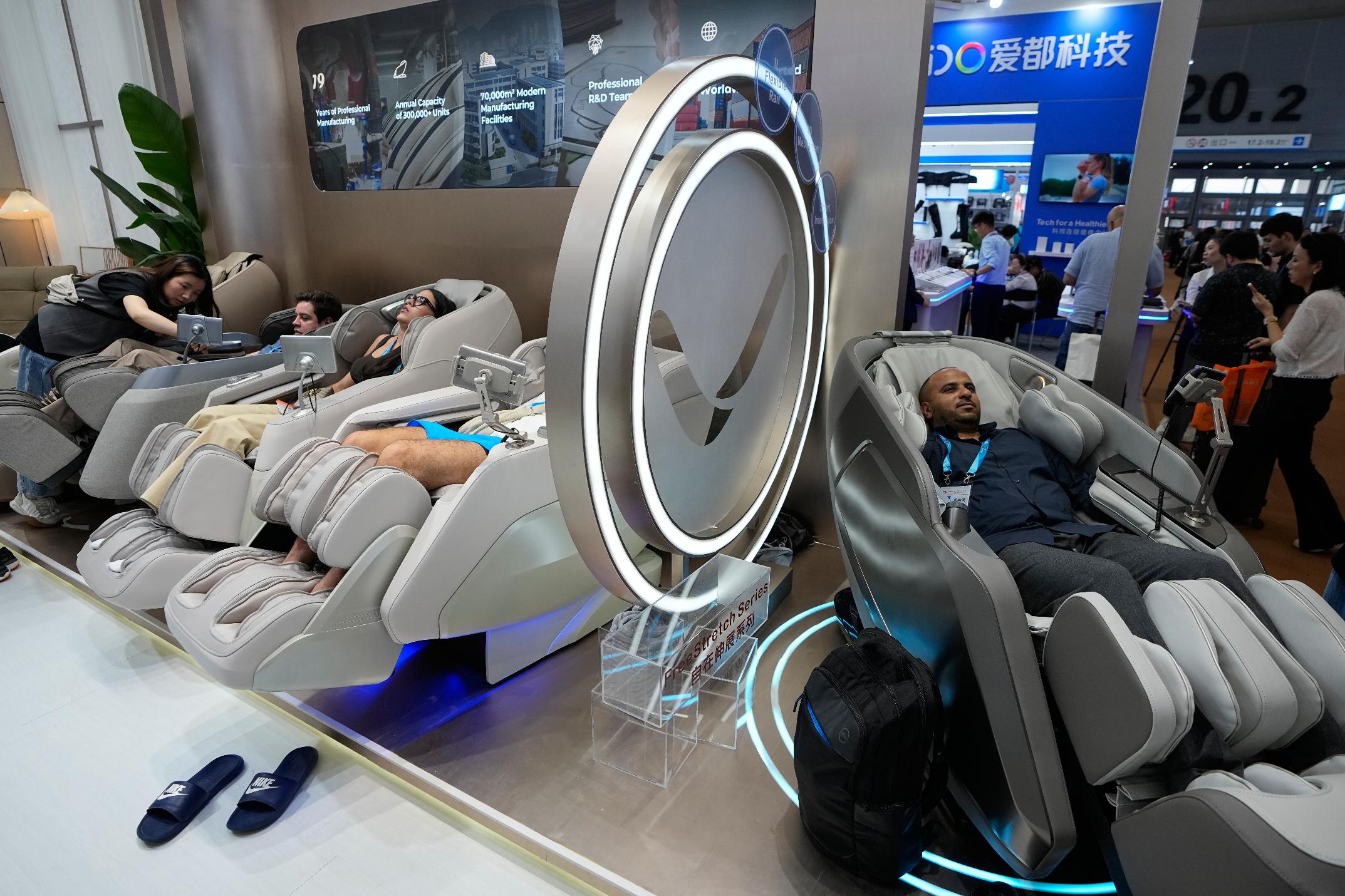 Foreign visitors try out the massage chairs at the Canton Fair, in Guangzhou, in southern China's Guangdong province, Wednesday, April 15, 2026. (AP Photo/Andy Wong)