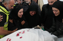 Family members of a paramedic who was killed in an Israeli airstrike, mourn over his body at a morgue, in Tyre, south Lebanon, Wednesday, March 25, 2026. (AP Photo/Hussein Malla)