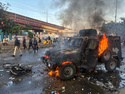 Paramilitary soldiers and police officers walk past a burning police's armoured vehicle, which was set on fire by Shiite Muslims during a protest over the killing of Iranian Supreme Leader Ayatollah Ali Khamenei, in Karachi, Pakistan, Sunday, March 1, 2026. (AP Photo/Muhammad Farooq)