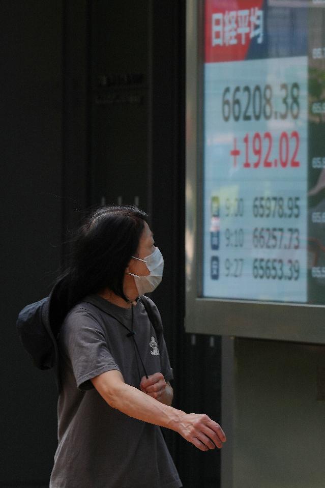 A person walks by an electronic stock board showing Japan's Nikkei index at a securities firm Monday, Aug. 24, 2026, in Tokyo. (AP Photo/Eugene Hoshiko)