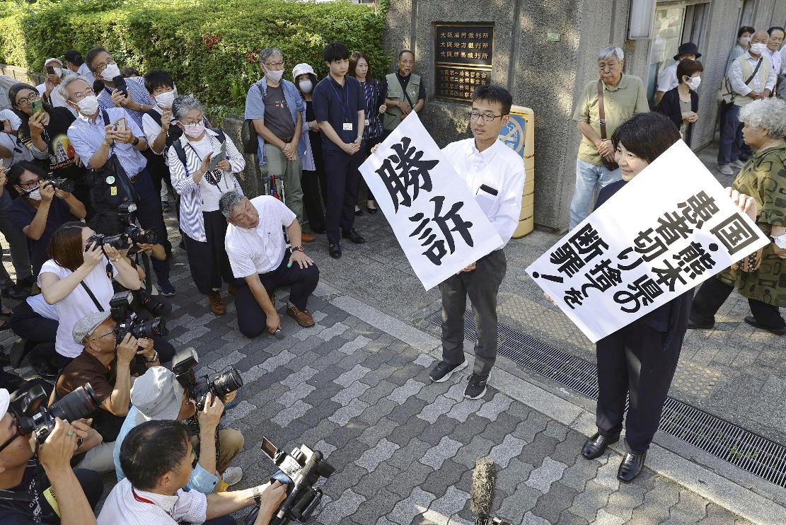 The banners, one of them reading "Victory" are shown by lawyers following the verdict outside the Osaka district court in Osaka, western Japan, Wednesday, Sept. 27, 2023. The court on Wednesday ordered the central government, the Kumamoto prefecture and a chemical company to recognize more than 120 plaintiffs as patients of the decades-old Minamata mercury poisoning and pay compensation they have been denied because they developed symptoms after moving away from the region. (Kyodo News via AP)