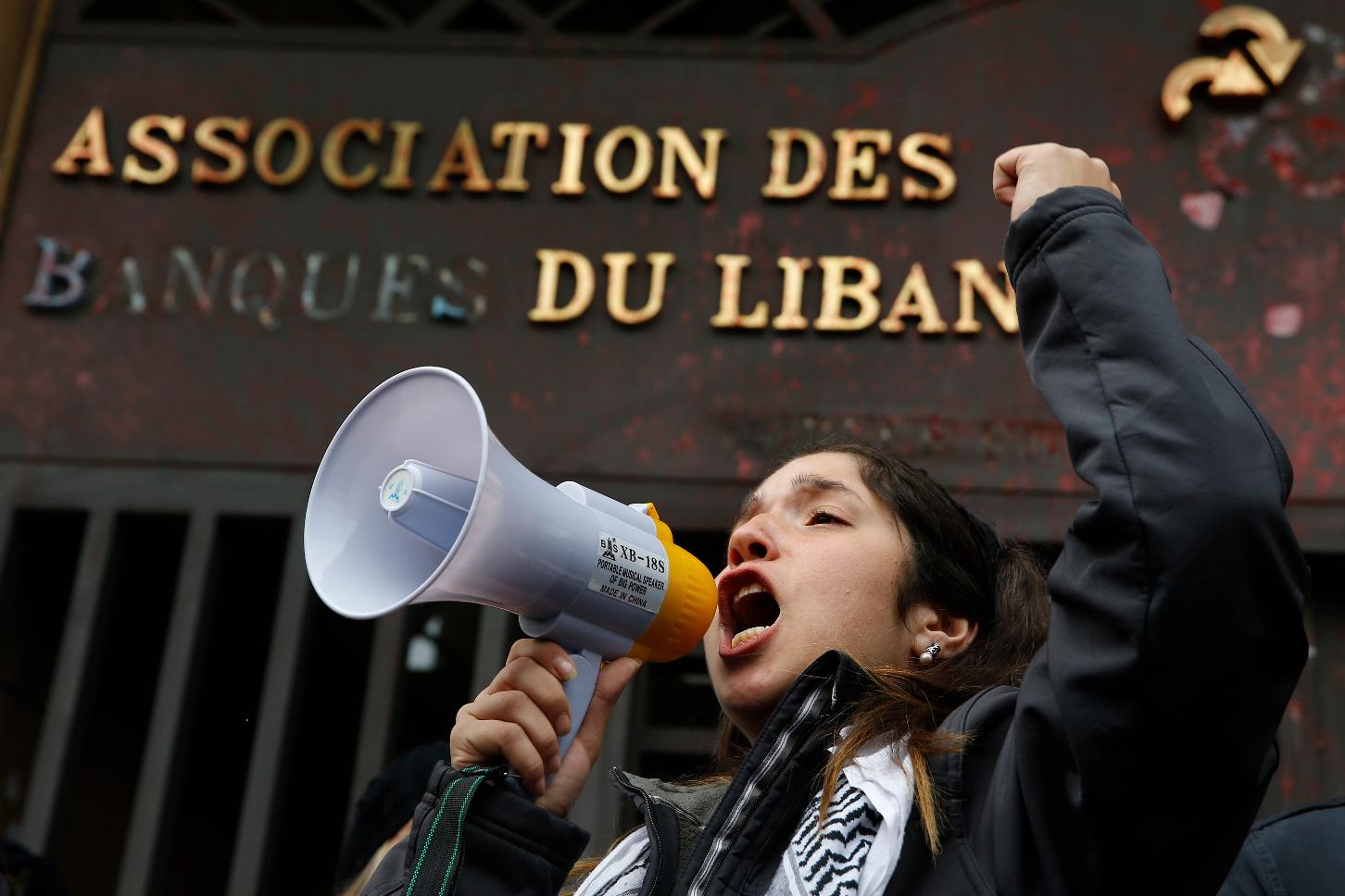 FILE - A protester leads a chant during ongoing protests against the Lebanese political class, in front of the building of the Lebanese Association of Banks in Beirut, Lebanon, Thursday, Dec. 26, 2019. (AP Photo/Bilal Hussein, File)