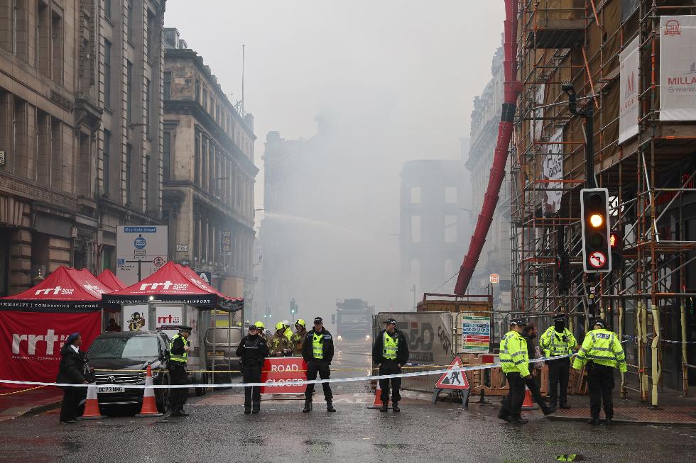 Firefighters damp down the remains of a fire which broke out in a building adjacent to Glasgow Central railway station on Sunday, in Glasgow, Scotland, Monday March 9, 2026. (Robert Perry/PA via AP)