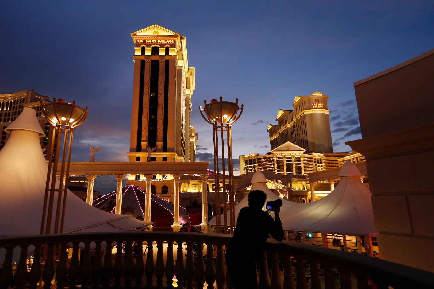 FILE - A man takes pictures of Caesars Palace hotel and casino in Las Vegas, Jan. 12, 2015. (AP Photo/John Locher, File)