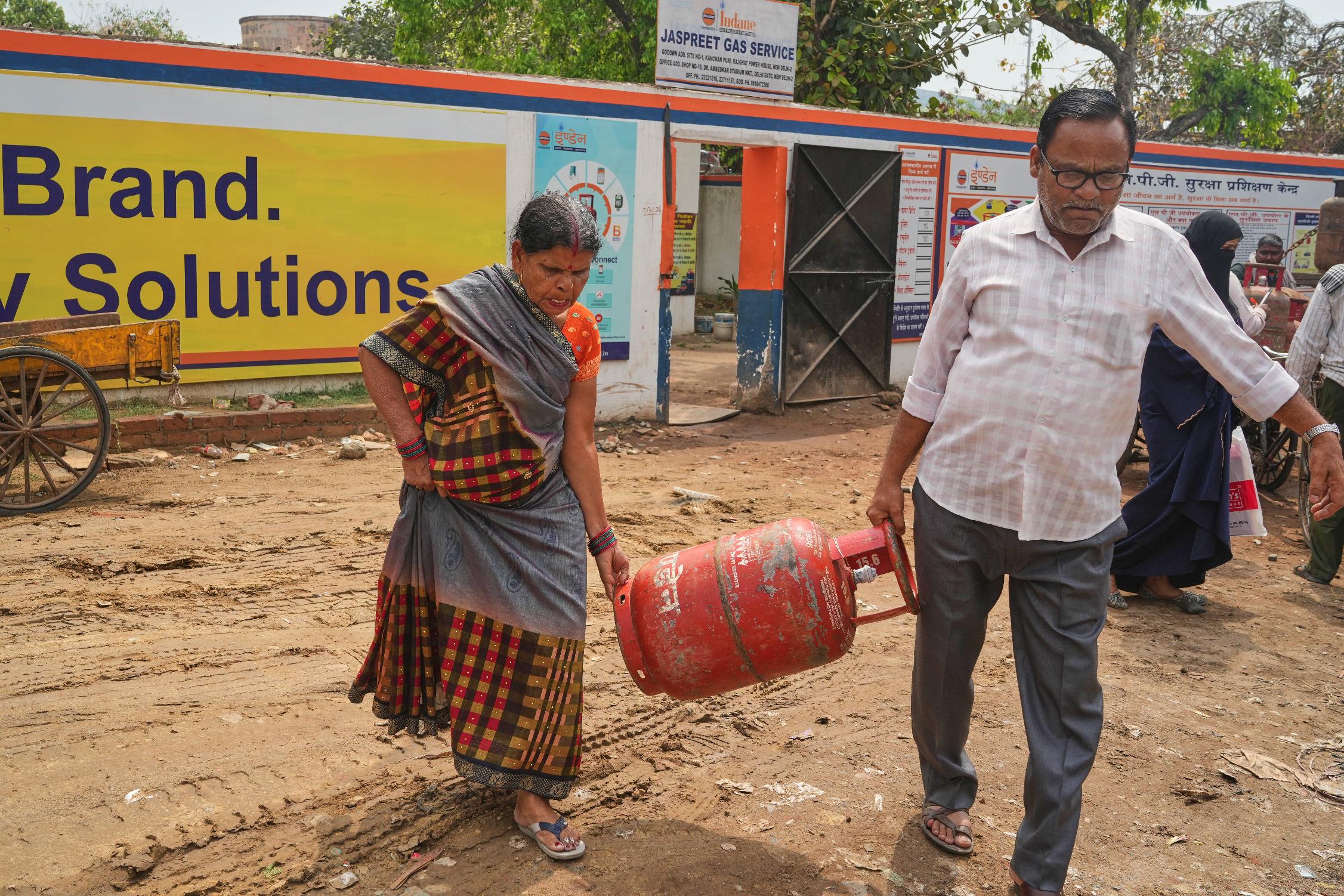 An elderly couple carries a gas cylinder to their home after collecting it from a depot, in New Delhi, Thursday, March 19, 2026. (AP Photo/Manish Swarup)