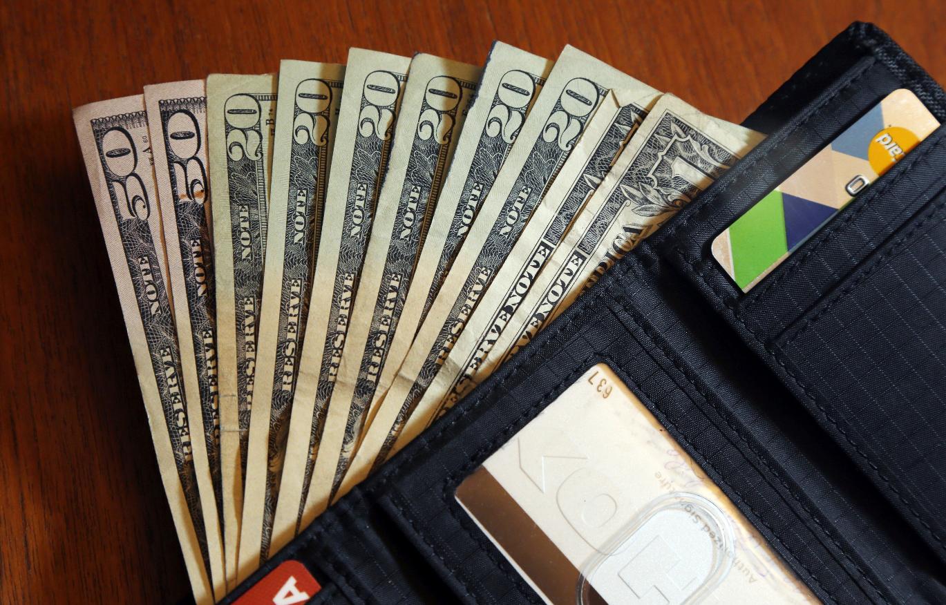 FILE - Cash is fanned out from a wallet in North Andover, Mass, June 15, 2018. (AP Photo/Elise Amendola, File)