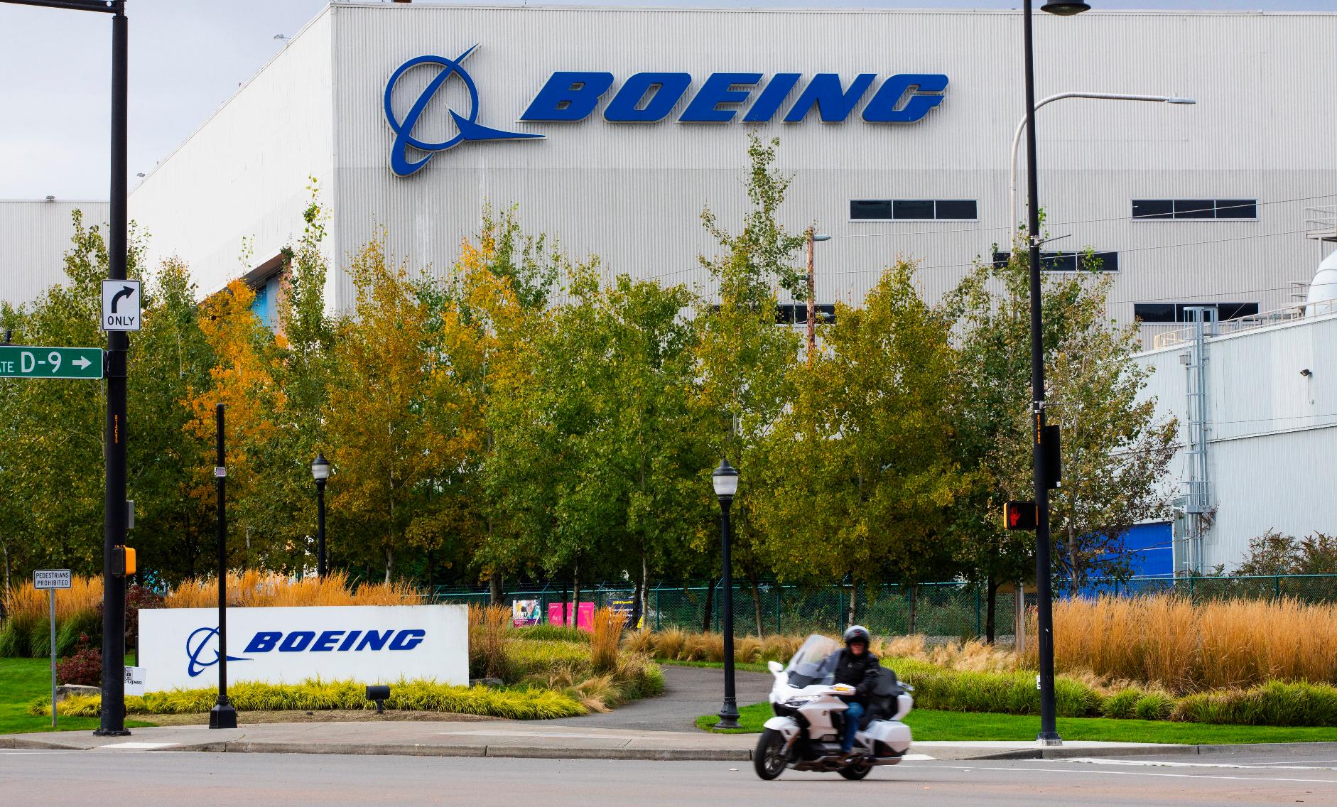 FILE - A motorcyclist cruises past the Renton, Wash., Boeing plant where 737's are built on Oct. 28, 2020. Boeing plans to make staffing cuts in the aerospace company's finance and human resources support services departments in 2023, with a loss of around 2,000 jobs, the company said Monday, Feb. 6, 2023. (Ellen M. Banner/The Seattle Times via AP, File)