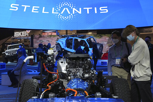 FILE - People look at the charging technology from the Jeep Wrangler 4xe at the Stellantis booth during the CES tech show Thursday, Jan. 6, 2022, in Las Vegas. Automaker Stellantis said Wednesday, Feb. 23, 2022 that it made 13.4 billion euros ($15.2 billion) in its first year after it was formed from the merger of Fiat Chrysler Automobiles and PSA Group.(AP Photo/Joe Buglewicz, File)
