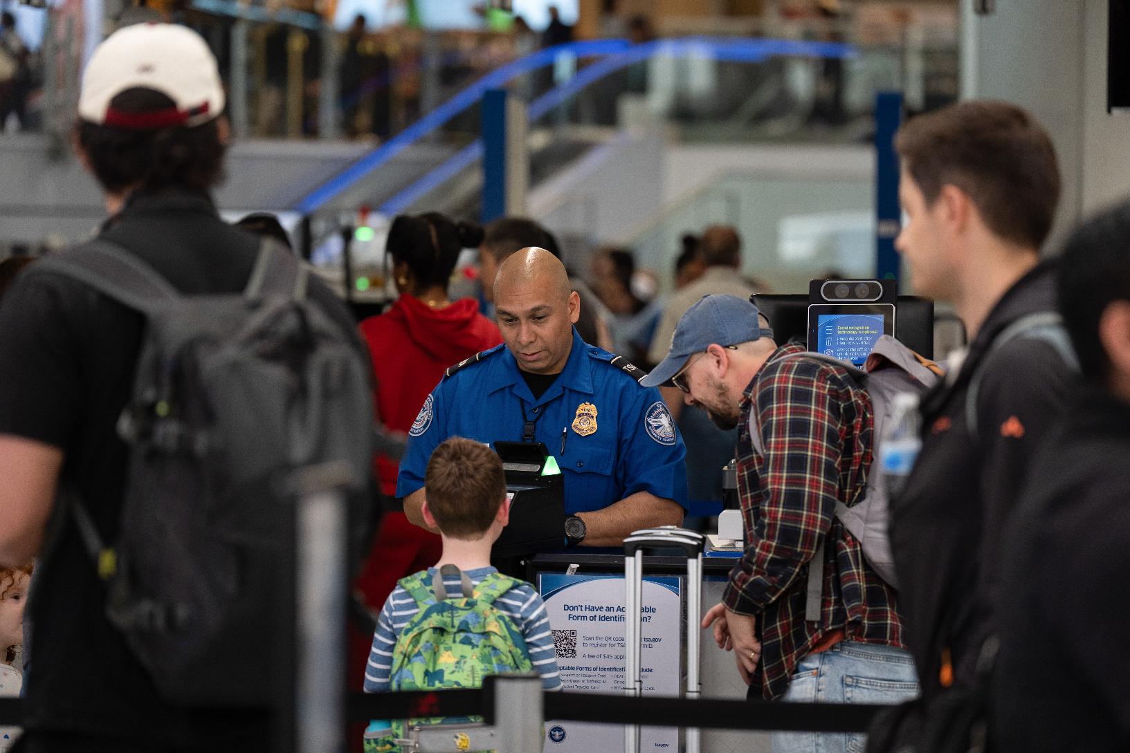 A TSA agent assists travelers at Los Angeles International Airport in Los Angeles, Friday, March 27, 2026. (AP Photo/Jae C. Hong)