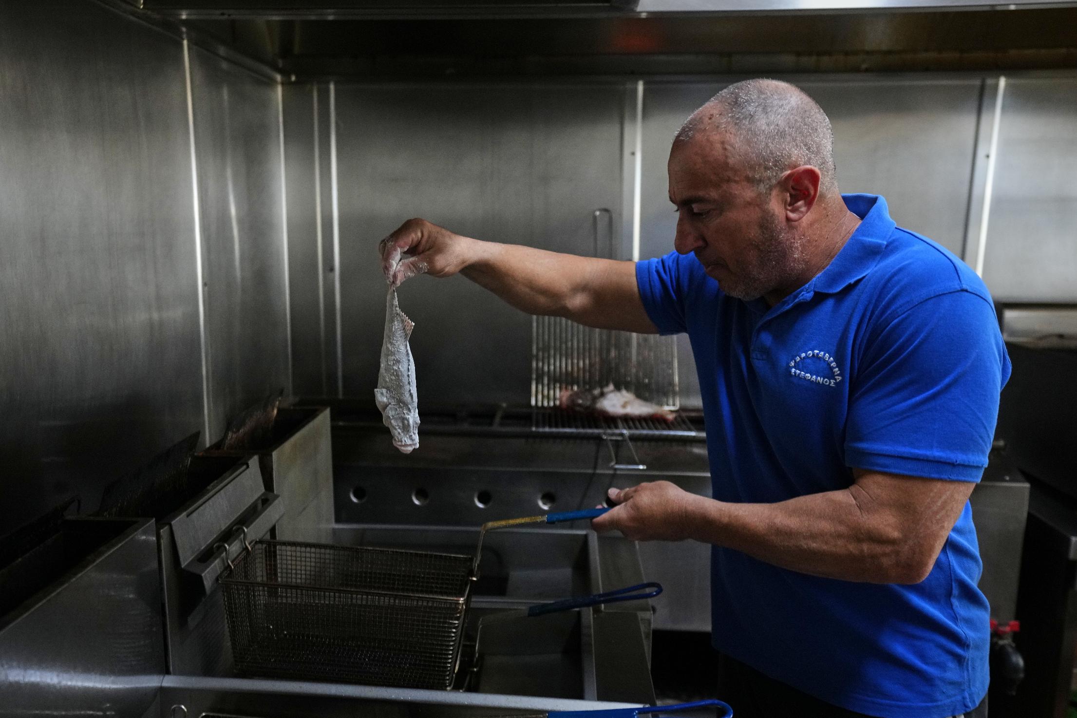 Stefanos Mentonis, owner of Stefanos restaurant, cooks lionfish in Larnaca, Cyprus, in the eastern Mediterranean, Thursday, Dec. 18, 2025. (AP Photo/Petros Karadjias)