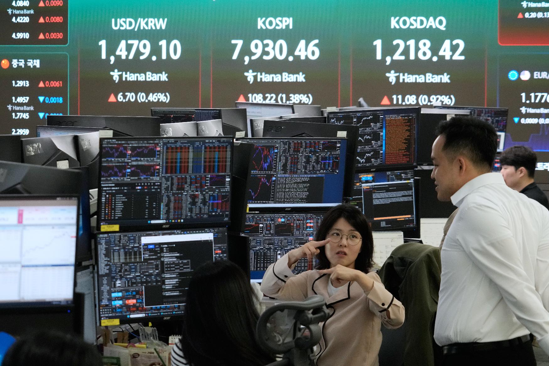 Currency traders work near a screen showing the Korea Composite Stock Price Index (KOSPI), top center, and the foreign exchange rate between U.S. dollar and South Korean won, top center left, at the foreign exchange dealing room of the Hana Bank headquarters in Seoul, South Korea, Tuesday, May 12, 2026. (AP Photo/Ahn Young-joon)