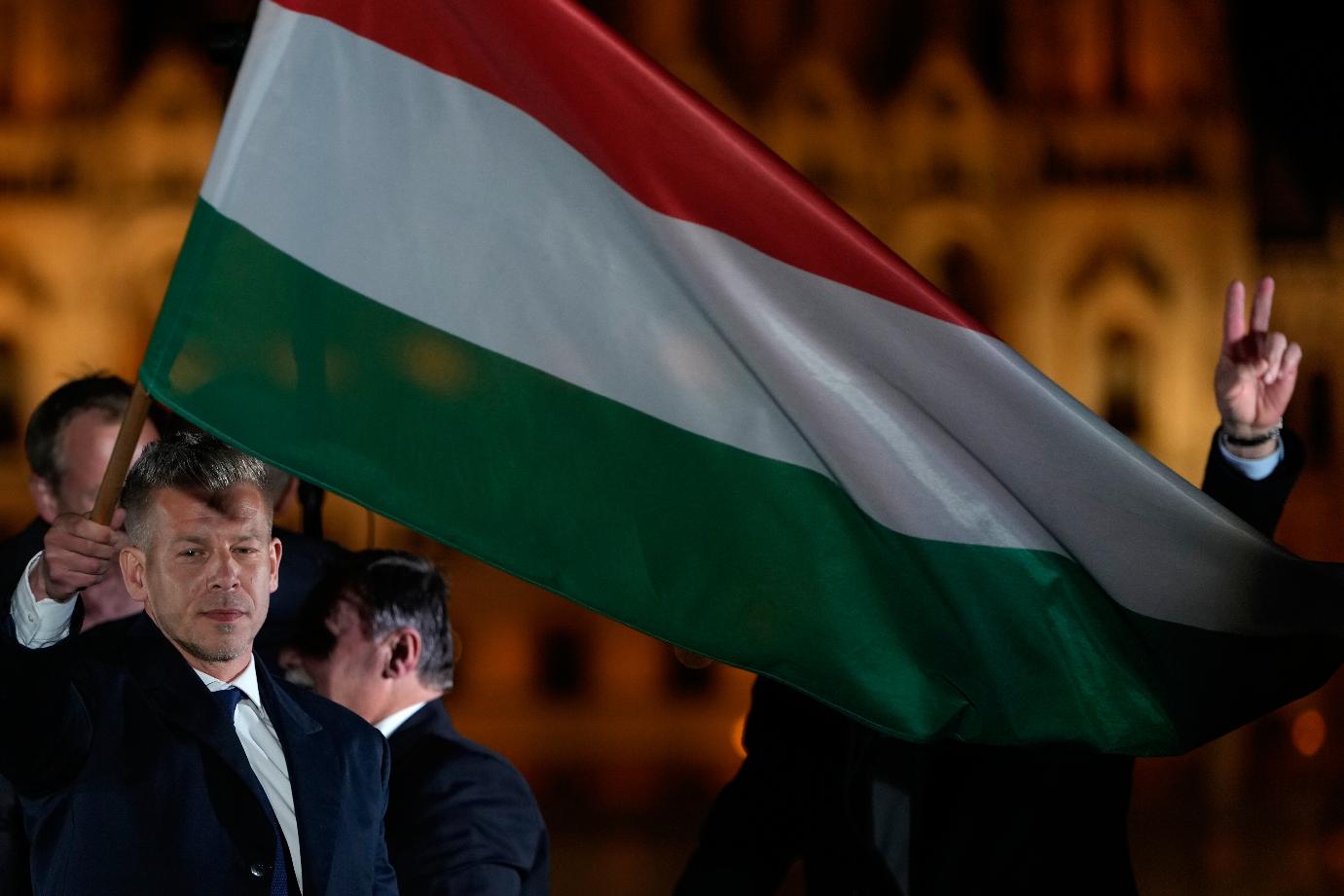 Peter Magyar, the leader of the opposition Tisza party waves a national flag after claiming victory in a parliamentary election in Budapest, Hungary, Sunday, April 12, 2026. (AP Photo/Darko Bandic)