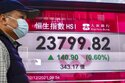 A man wearing a face mask walks past a bank's electronic board showing the Hong Kong share index in Hong Kong, Thursday, Dec. 2, 2021. Asian stock markets were mixed Thursday after a turbulent day on Wall Street as traders tried to forecast the impact of the coronavirus's omicron variant. (AP Photo/Kin Cheung)