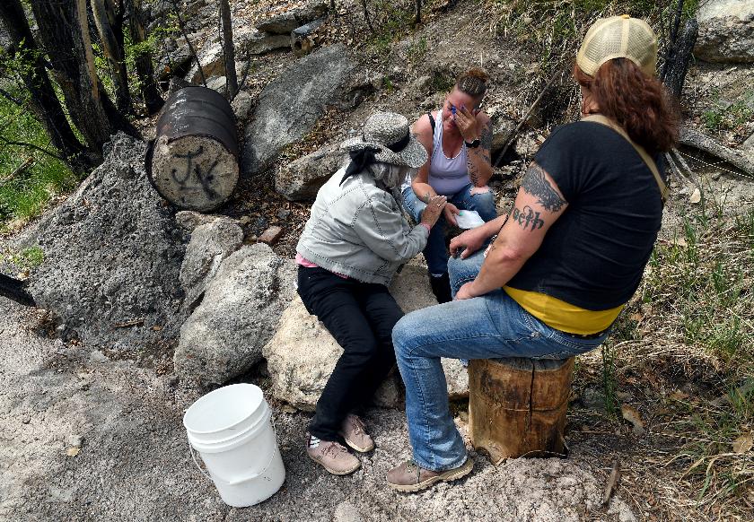 Crystina Page, whose son's body was among nearly 200 found decomposing in a southern Colorado funeral home in 2023, is comforted at a memorial site for the victims in Colorado Springs, Colo., on Wednesday, April 22, 2026. (AP Photo/Thomas Peipert)