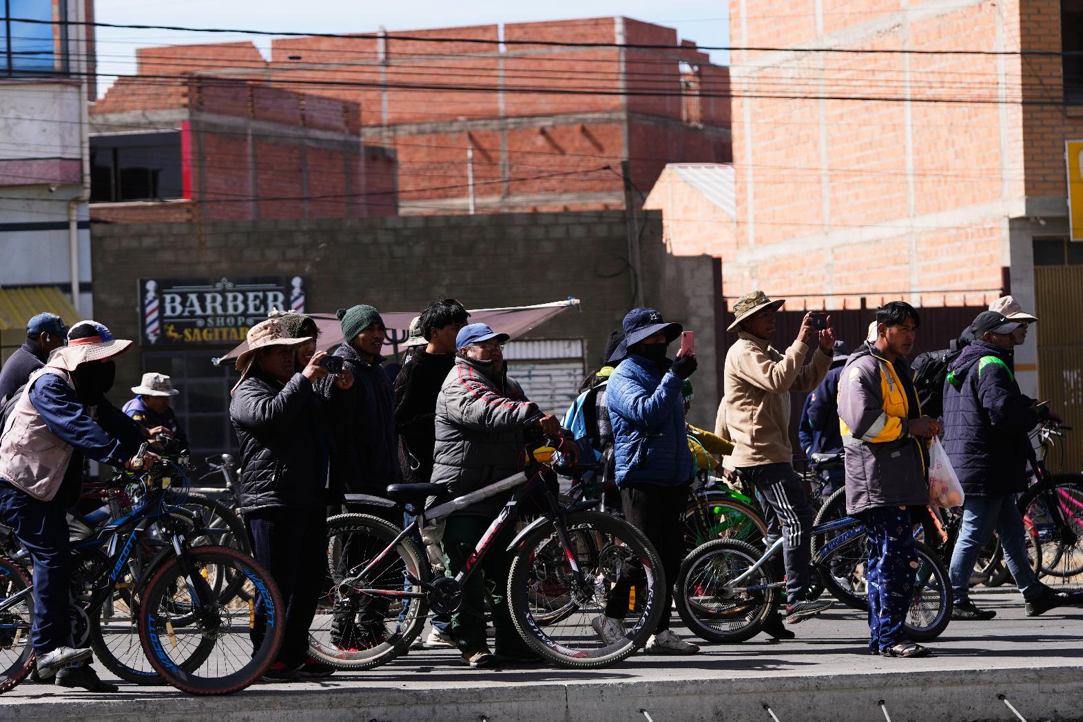 Residentes take pictures at police clearing a highway blocked by protesters after President Rodrigo Paz declared a state of emergency in El Alto, Bolivia, Saturday, June 20, 2026. (AP Photo/Juan Karita)