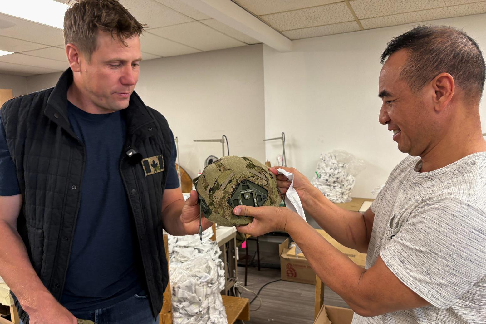 Wuxly CEO James Yurichuk and garment factory owner Aaron Ly inspect military helmet covers on July 20, 2026, in North York, Ontario. (AP Photo/Kelvin Chan) CORRECTION: Family name corrected to Ly, instead of Lyand.