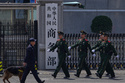 FILE - Paramilitary soldiers and a police officer with a sniffer dog march past the main entrance gate of China's Ministry of Commerce, in Beijing, on April 3, 2025. (AP Photo/Andy Wong, File)