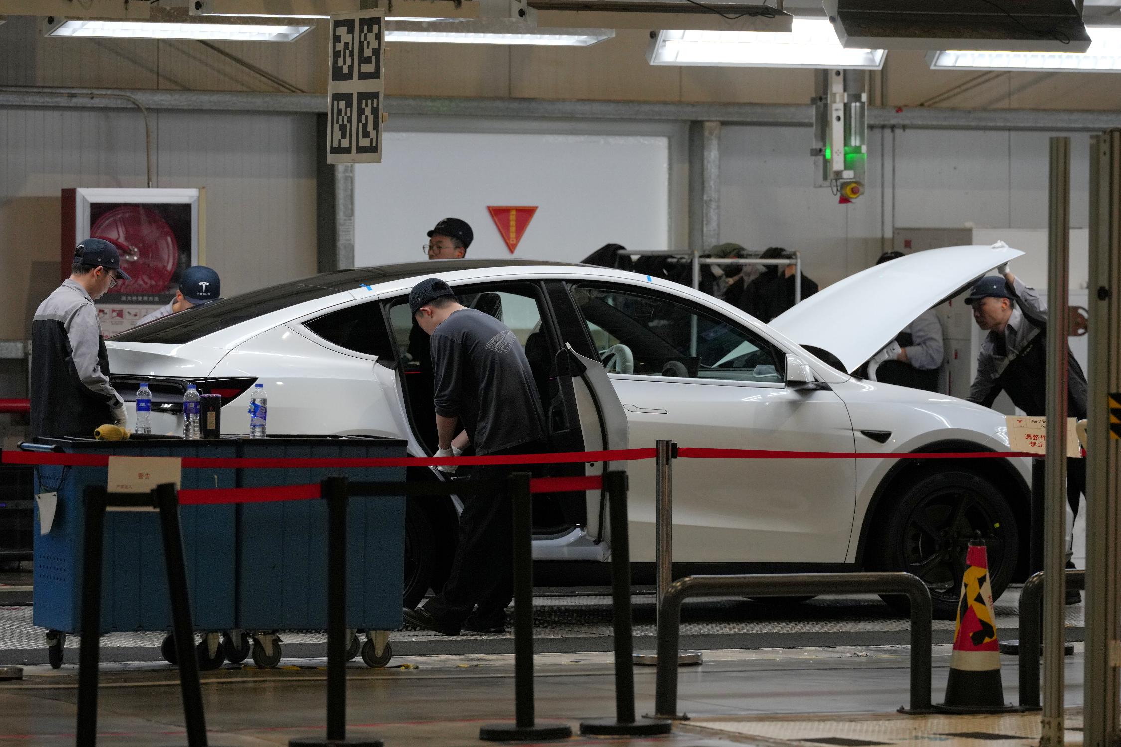 FILE - People work on the Tesla Model Y production line at the Tesla Gigafactory assembly plant during a media organized tour, in Shanghai, China, Tuesday, April 14, 2026. (AP Photo/Andy Wong, File)