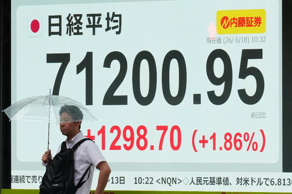 A man stands by a screen showing Japan's Nikkei 225 index at a securities firm in Tokyo, Thursday, June 18, 2026. (AP Photo/Hiro Komae)