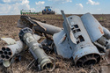 Fragments of Russian missiles lie on the field against the background of the working farmers near the front line in the Kharkiv region, Ukraine, Friday, May 22, 2026. (AP Photo/Andrii Marienko)