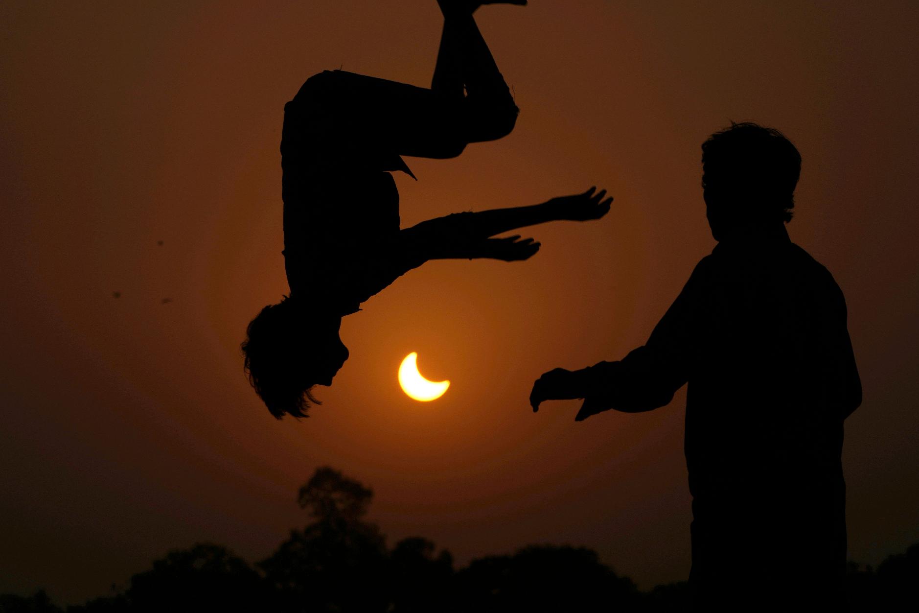 FILE - The partial solar eclipse is framed by youngsters jumping on a trampoline in the outskirts of Lahore, Pakistan, Oct. 25, 2022. (AP Photo/K.M. Chaudary, File)