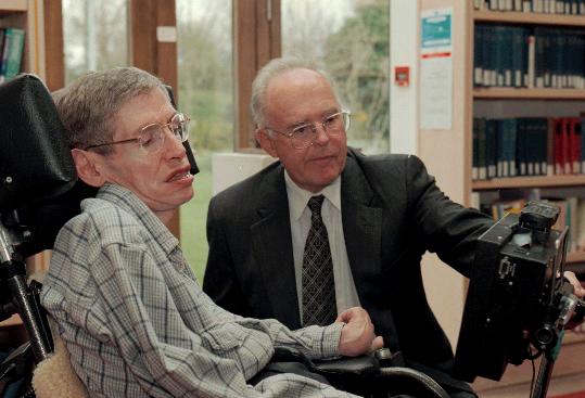 FILE Physicist Stephen Hawking, left, looks at a new custom-built computer designed especially for him with Dr. Gordon Moore of the Intel Corporation in the library of The Issac Newton Institute of Mathematics in Cambridge, England, Thursday, March 20, 1997. Moore, the Intel Corp. co-founder who set the breakneck pace of progress in the digital age with a simple 1965 prediction of how quickly engineers would boost the capacity of computer chips, has died. He was 94. Intel and the Gordon and Betty Moore Foundation say Moore died Friday, March 24, 2023 at his home in Hawaii. (AP Photo, File)