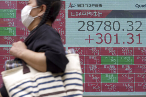 A person wearing a protective mask walks in front of an electronic stock board showing Japan's Nikkei 225 index at a securities firm Friday, Aug. 26, 2022, in Tokyo. Asian stock markets followed Wall Street higher on Friday ahead of speech by the Federal Reserve chair that investors hoped would shed light on plans for more interest rate hikes. (AP Photo/Eugene Hoshiko)