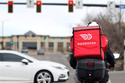 FILE - A food delivery rider waits for the traffic light to change March 30, 2020, in Lone Tree, Colo. (AP Photo/David Zalubowski, File)