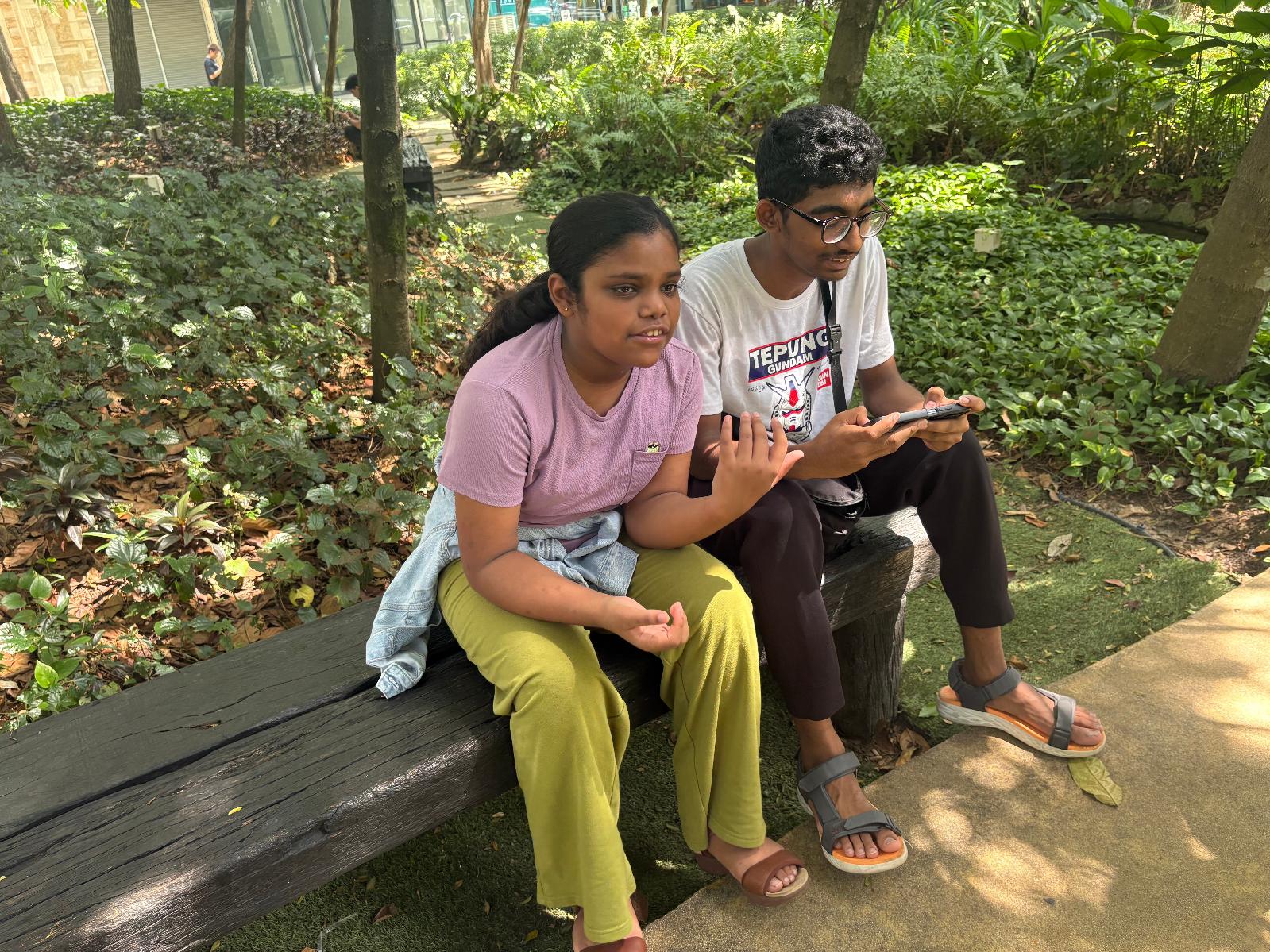 Siblings Saaradha Saravanan, 12, left, and Aadhavan Saravanan, 15, sit in a park in Petaling Jaya, near Kuala Lumpur Malaysia Monday, June 1, 2026. (AP Photo/Eileen Ng)
