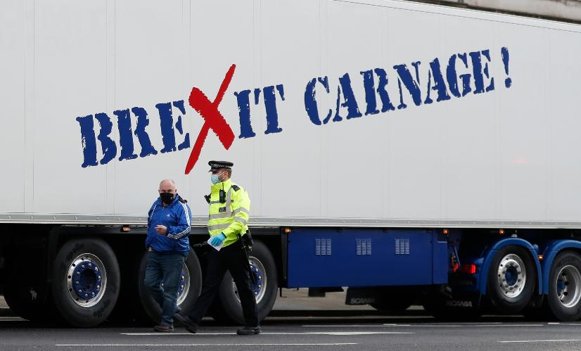 FILE - A policeman escorts the driver of a shellfish export truck as he is stopped for an unnecessary journey in London, Monday, Jan, 18, 2021. (AP Photo/Alastair Grant, File)