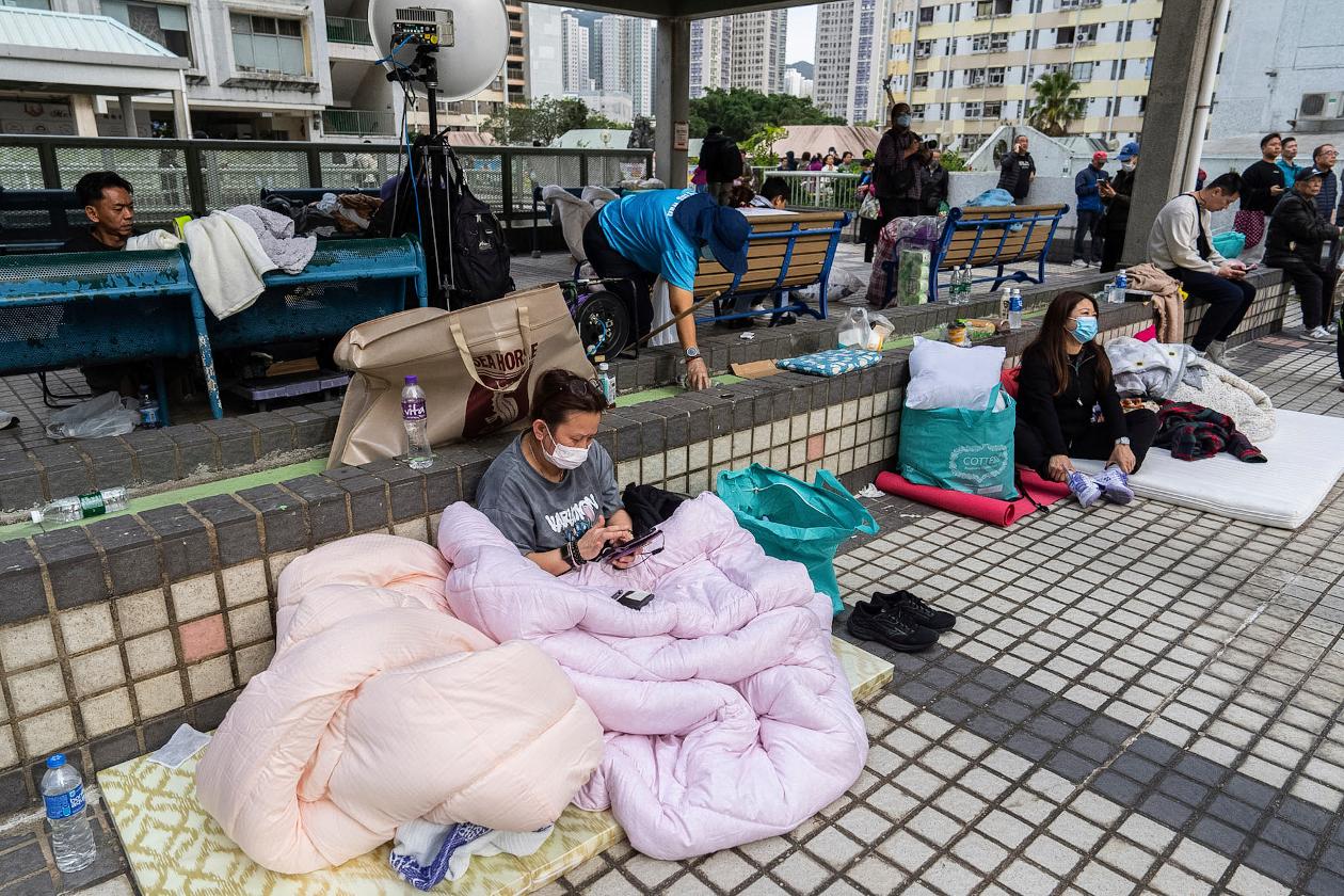 Residents rest nearby in the aftermath of a fire which broke out Wednesday at Wang Fuk Court, a residential estate in the Tai Po district of Hong Kong's New Territories, Thursday, Nov. 27, 2025. (AP Photo/Chan Long Hei)