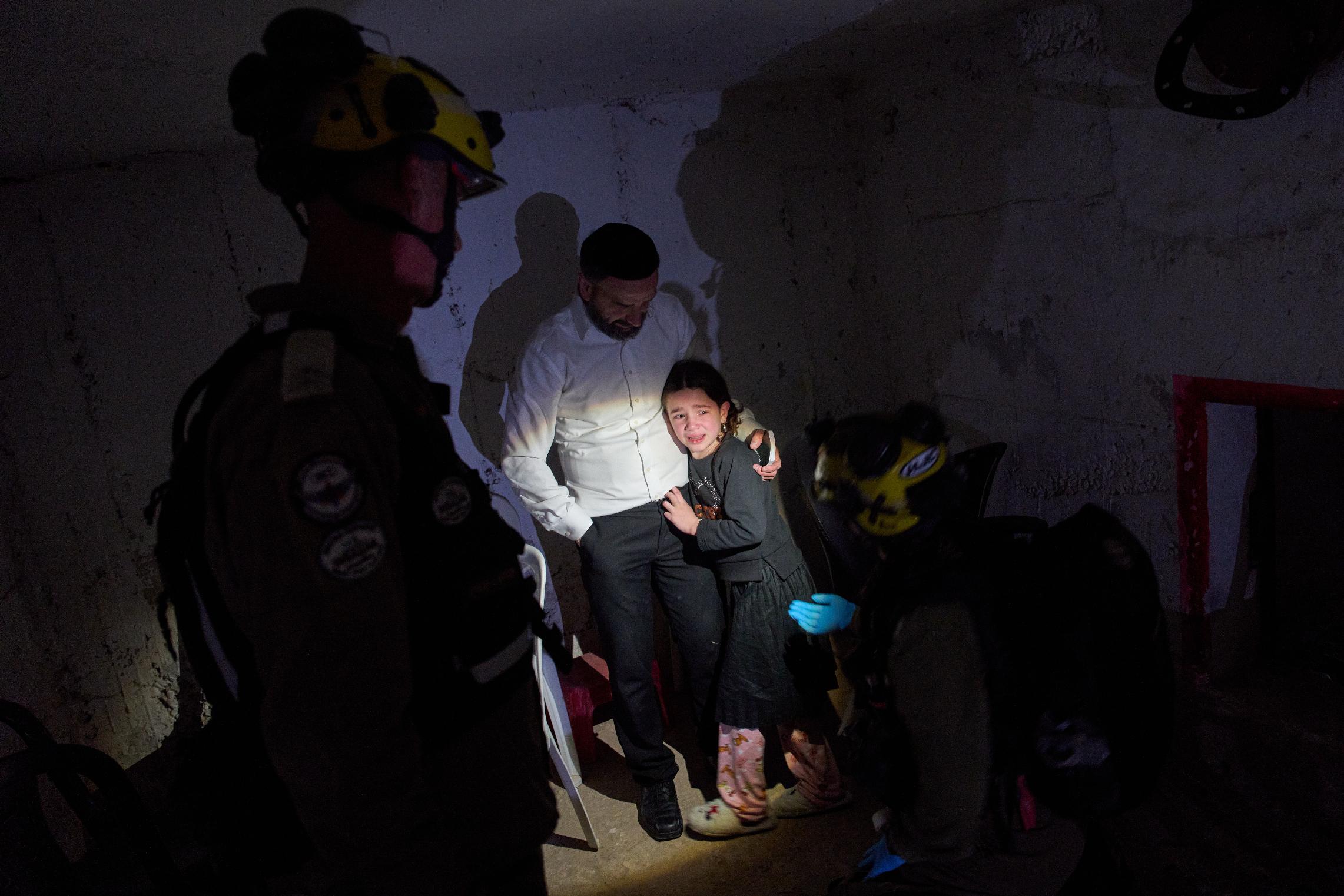 A young girl is comforted by her father and Israeli soldiers as they take cover in a bomb shelter during air raid sirens warning of incoming Iranian missile strikes in Bnei Brak, Israel, Wednesday, April 1, 2026. (AP Photo/Oded Balilty)