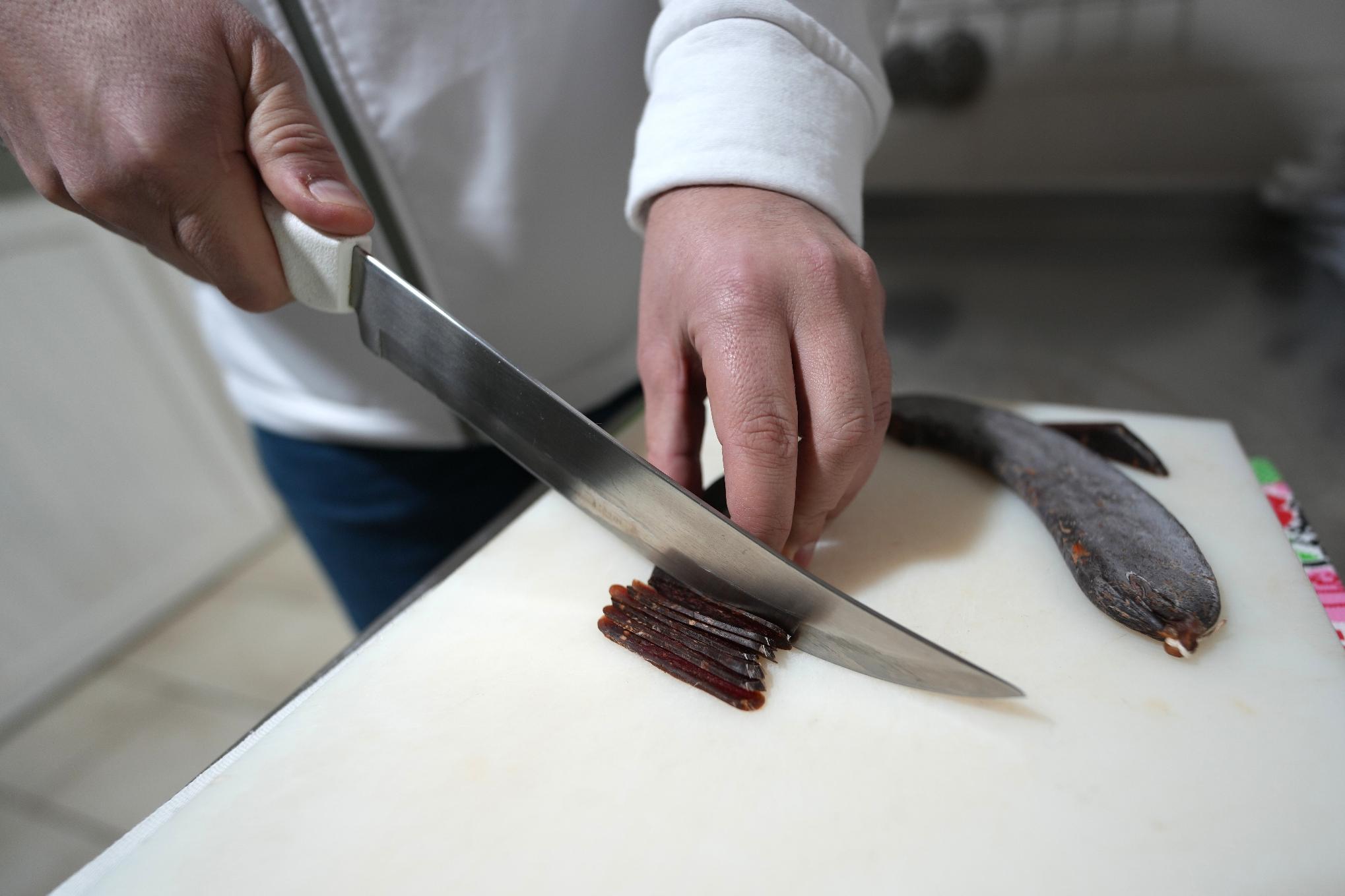 Misa Rajic prepares ironed sausage at his home in Pirot, Serbia, on Feb. 13, 2026. (AP Photo/Darko Vojinovic)