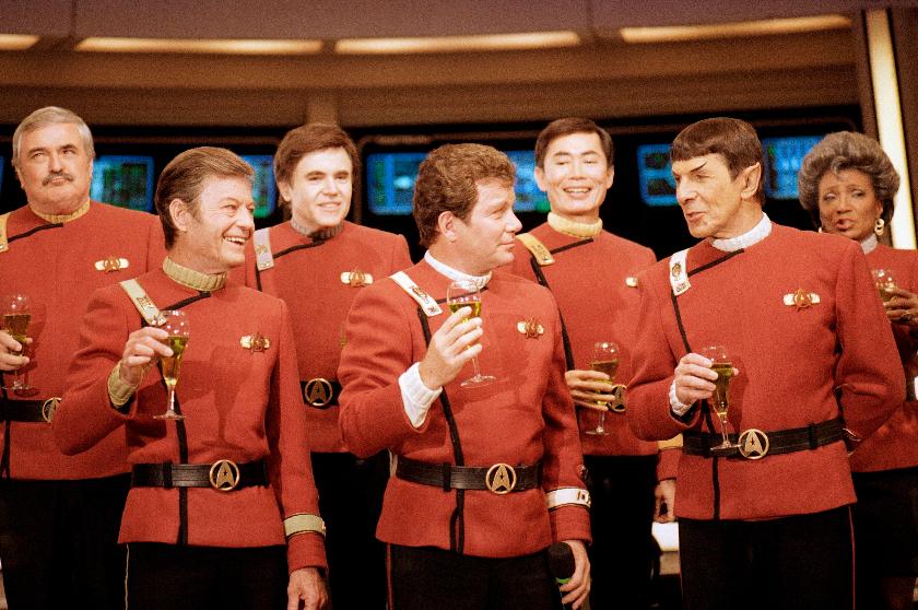 FILE- Members of the "Star Trek" crew, from left, James Doohan, DeForest Kelley, Walter Koenig, William Shatner, George Takei, Leonard Nimoy, and Nichelle Nichols, toast the newest "Star Trek" film at Paramount Studios on Dec. 28, 1988. (AP Photo/Bob Galbraith, File)