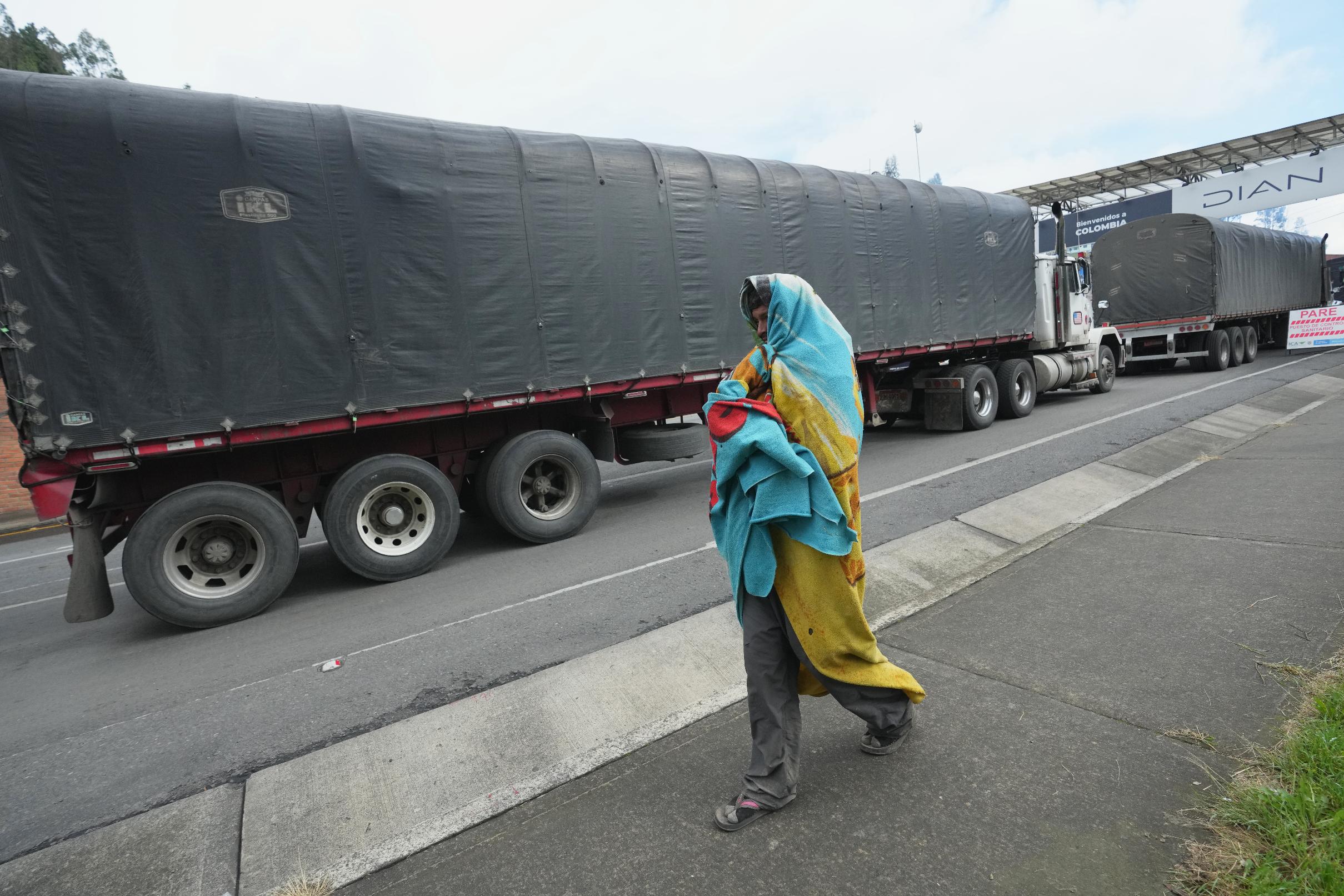 A man walks next to trucks heading to the border with Colombia, in Rumichaca, Ecuador, Friday, Jan. 23, 2026. (AP Photo/Dolores Ochoa).