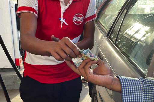FILE - A driver hands over Myanmar kyats to an attendant as payment for fuel at a gas station in Botahtaung township in Yangon, Myanmar on Nov. 12, 2021. Army-ruled Myanmar’s economy remains fragile as civil strife, inflation and onerous policy decisions add to troubles facing farmers and businesses, reports by the World Bank and other experts said Thursday, July 21, 2022. (AP Photo, File)