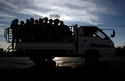 FILE -In this Dec. 3, 2018 photo, garment factory workers ride a truck as they go home after a day's work at outside Phnom Penh, Cambodia. (AP Photo/Heng Sinith, File)