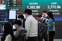 Currency traders watch monitors near a screen showing the Korea Composite Stock Price Index (KOSPI), right, and the foreign exchange rate between U.S. dollar and South Korean won at the foreign exchange dealing room of the Hana Bank headquarters in Seoul, South Korea, Thursday, March 19, 2026. (AP Photo/Ahn Young-joon)