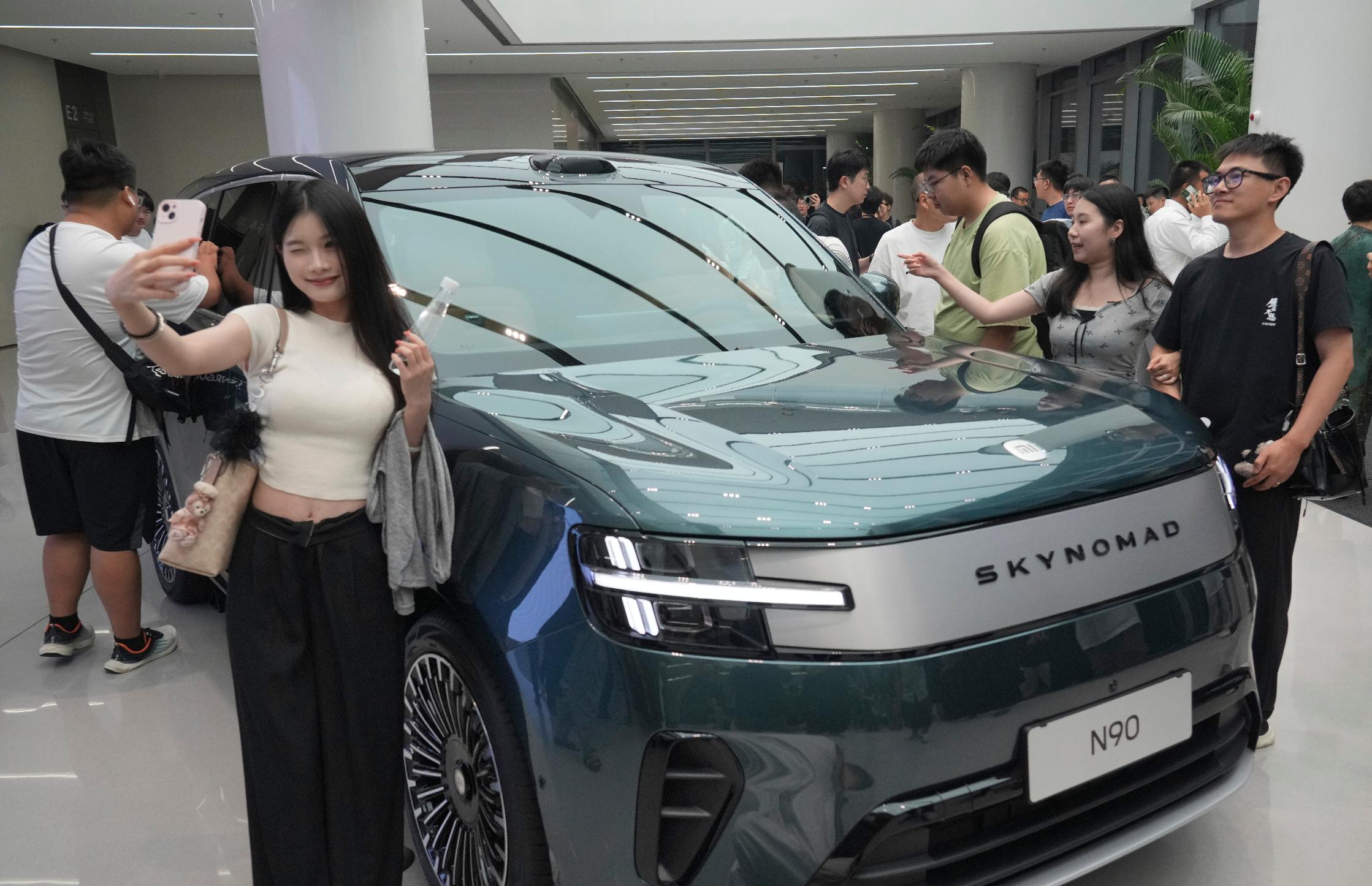 A visitor takes a selfie with the electric vehicle Xiaomi skynomad series during a launch event held in Beijing, China, Thursday, July 30, 2026. (AP Photo/Achmad Ibrahim)