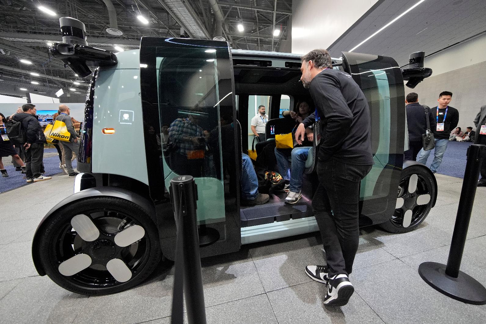 FILE - People view a Zoox self-driving vehicle at the company's booth during the CES tech show, Jan. 7, 2025, in Las Vegas. (AP Photo/John Locher, File)