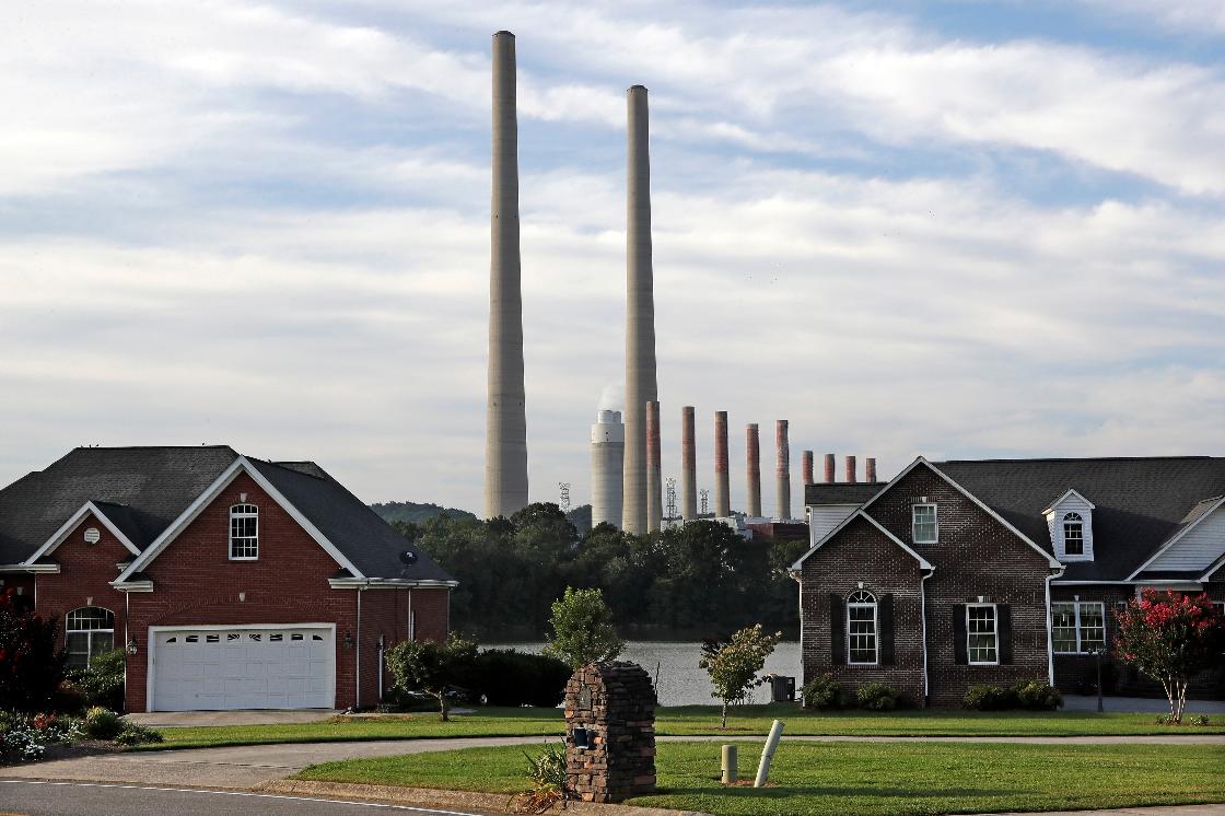 FILE - The Kingston Fossil Plant smokestacks rise above the trees behind homes in Kingston, Tenn, Aug. 7, 2019. (AP Photo/Mark Humphrey, File)