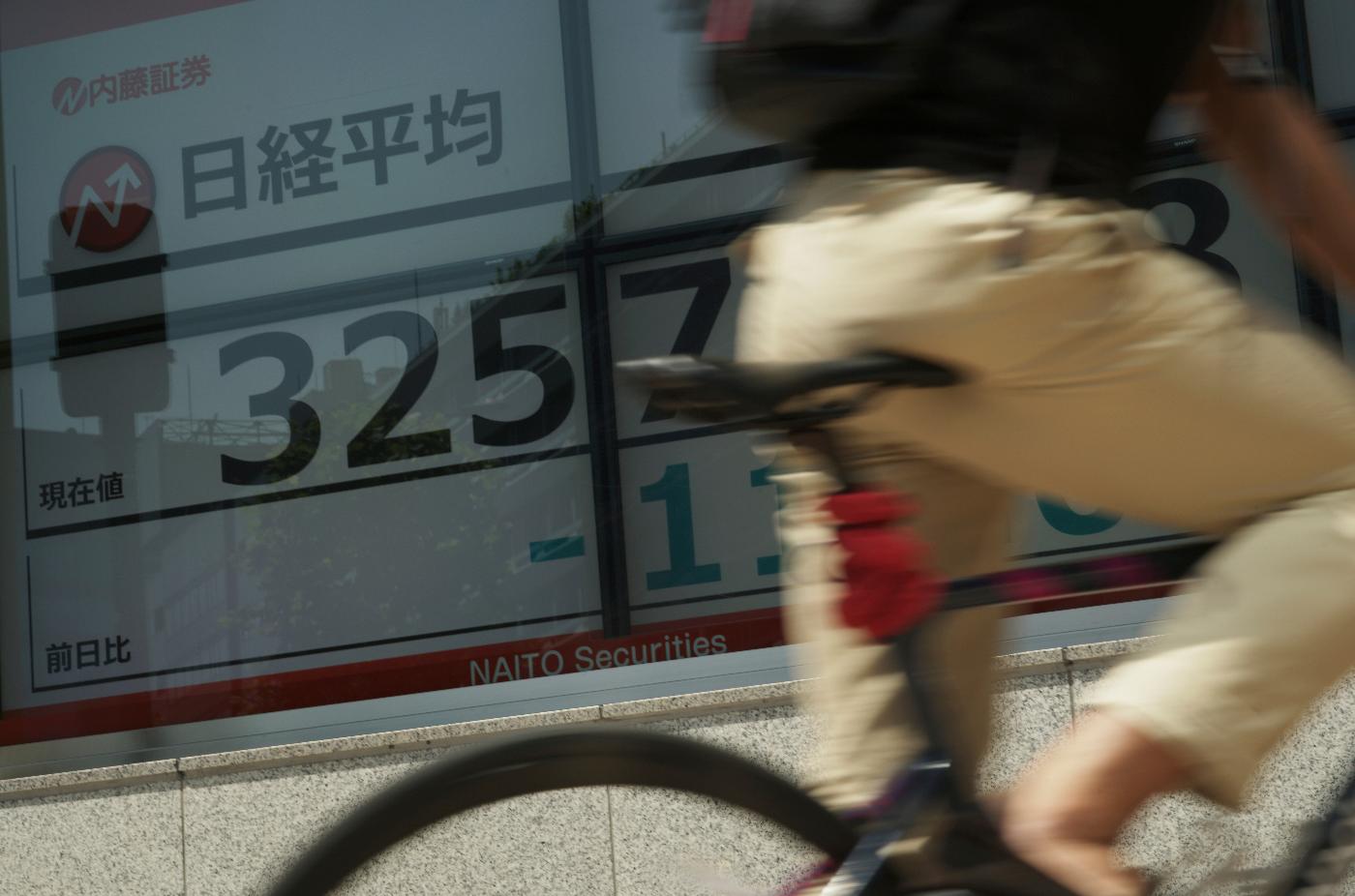 A person bikes past monitors showing Japan's Nikkei 225 index at a securities firm in Tokyo, Wednesday, July 26, 2023. Asian stock markets retreated Wednesday after Wall Street hit a 15-month high ahead of a Federal Reserve meeting that traders hope will end with the final increase in this interest rate cycle. (AP Photo/Hiro Komae)