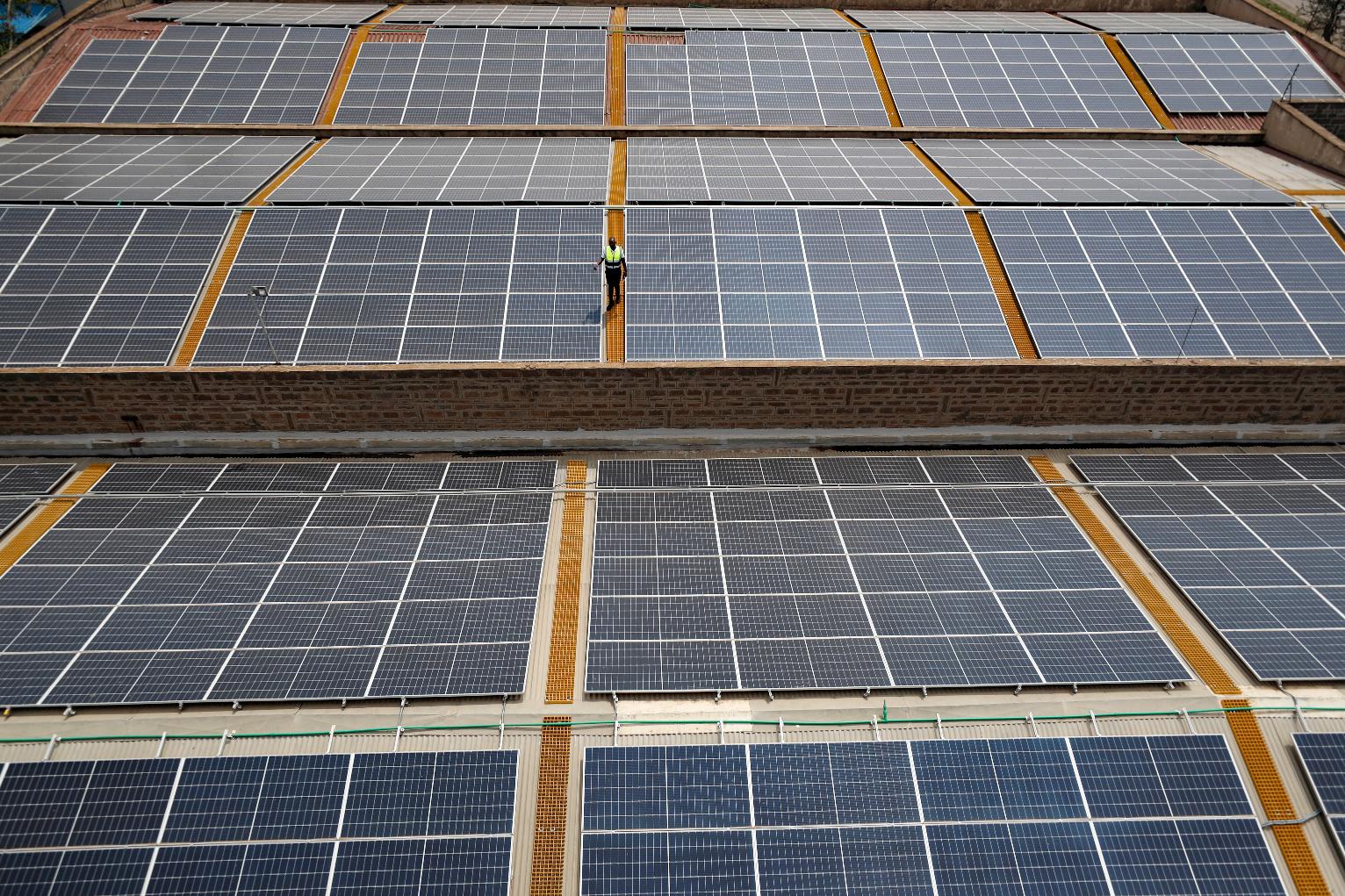 FILE - Mark Munyua, CP solar's technician, examines solar panels on the roof of a company in Nairobi, Kenya, Sept. 1, 2023. (AP Photo/Brian Inganga, File)