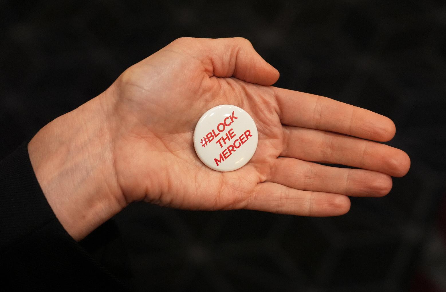 A pin expressing opposition to the proposed Paramount-Warner Bros. Discovery merger is displayed during CinemaCon 2026 on Tuesday, April 14, 2026, at Caesars Palace in Las Vegas. (AP Photo/Chris Pizzello)