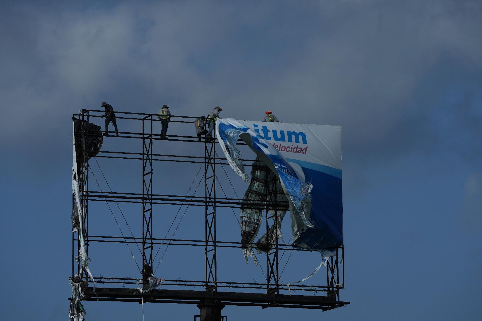 Workers remove an advertisement from a billboard for protection ahead of Hurricane Beryl's expected arrival, in Playa del Carmen, Mexico, Wednesday, July 3, 2024. (AP Photo/Fernando Llano)