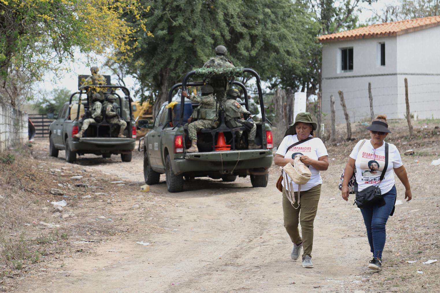 Members of a group that searches for missing people walk alongside soldiers in El Verde, Sinaloa state, Mexico, Monday, Feb. 8, 2026. (AP Photo/Juvencio Villanueva)