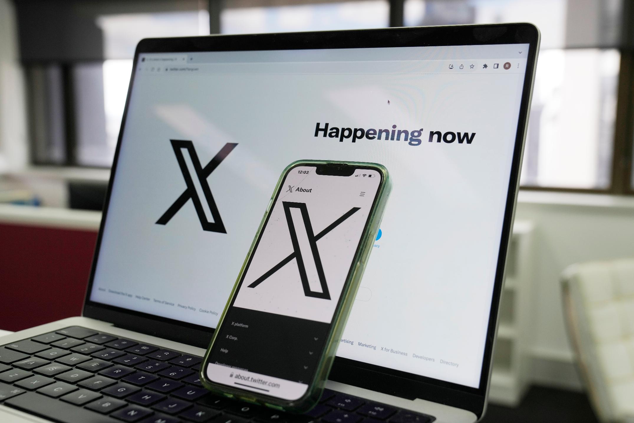 FILE - The opening page of X is displayed on a computer and phone, Oct. 16, 2023, in Sydney. The social media platform X says it will now allow people to show consensual adult content, as long as it is clearly labeled as such. The move formalizes a policy already in place when the platform was known as Twitter, before billionaire Elon Musk purchased it in 2022. (AP Photo/Rick Rycroft, File)